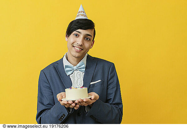 Smiling man holding 18th birthday cake in studio