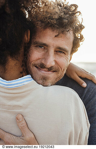 Smiling man hugging girlfriend at beach