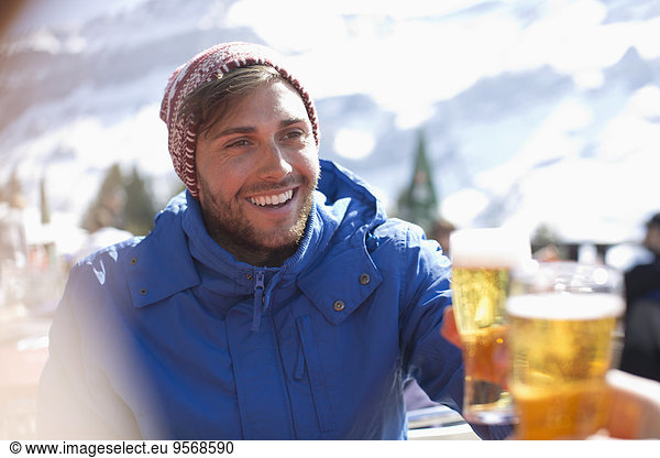 Smiling man in warm clothing drinking beer outdoors