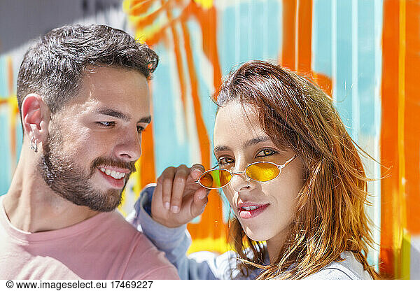 Smiling man looking at woman with sunglasses on sunny day