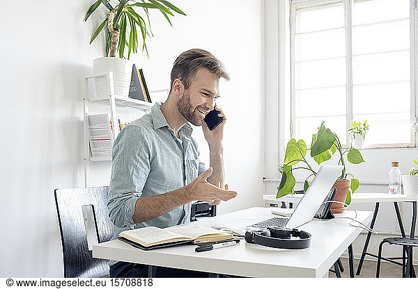 Smiling man on the phone at desk in office