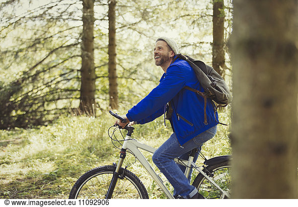 Smiling man riding mountain biking in woods