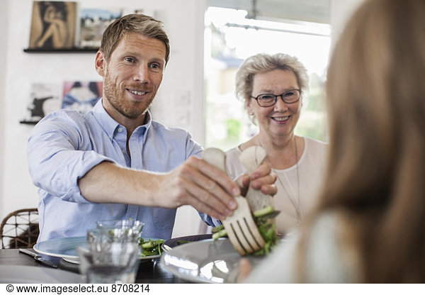 Smiling man serving salad to girl at home