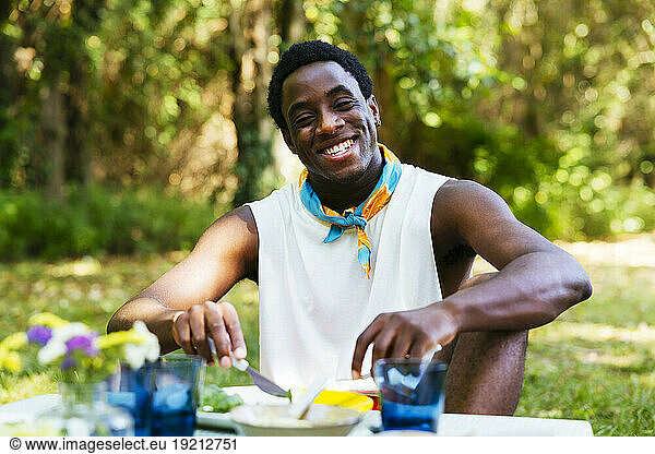 Smiling man sitting at picnic table in garden