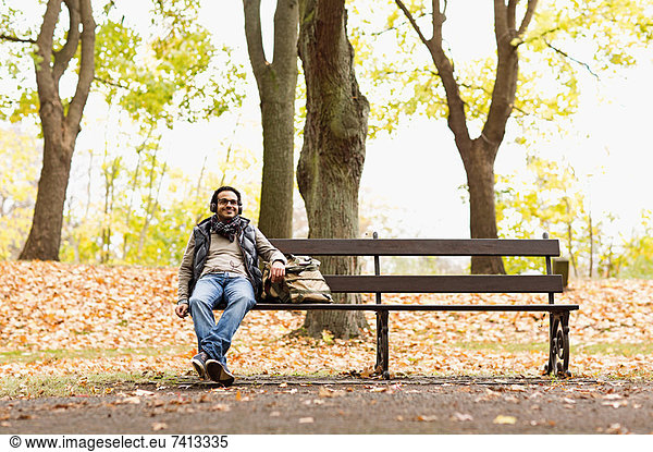 Smiling man sitting on park bench