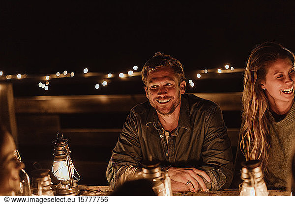Smiling man sitting with female friend in restaurant at night