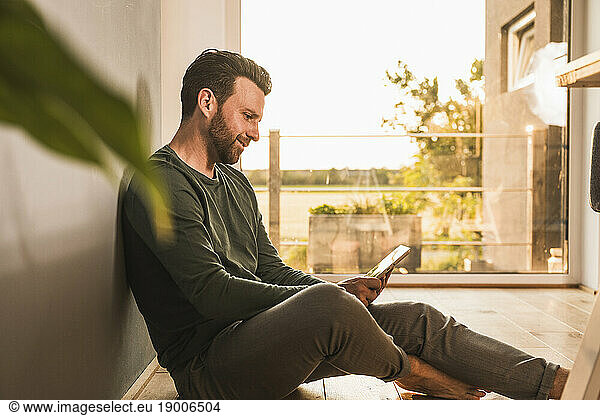 Smiling man using tablet PC on floor