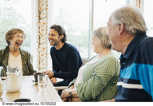 Smiling man visiting his grandmother and her friends at retirement home