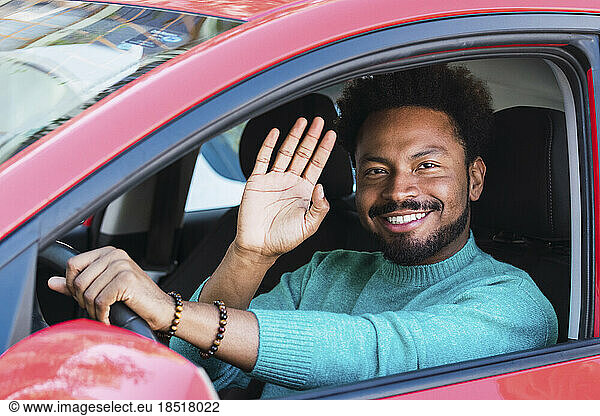 Smiling man waving in car