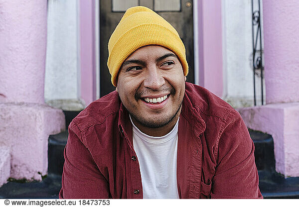 Smiling man wearing knit hat in front of door
