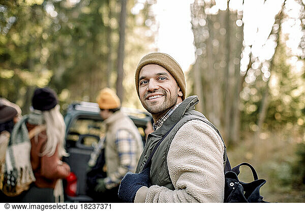 Smiling man wearing warm clothing contemplating in forest