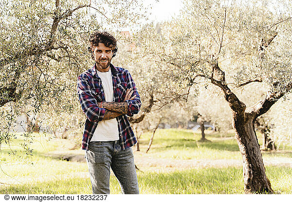 Smiling man with arms crossed in olive orchard
