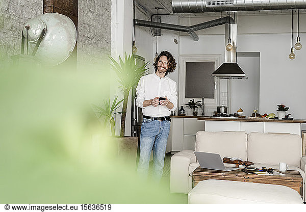 Smiling man with cell phone at home