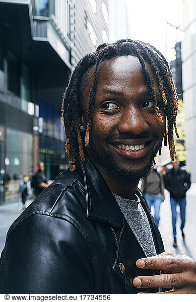 Smiling man with dreadlocks in city