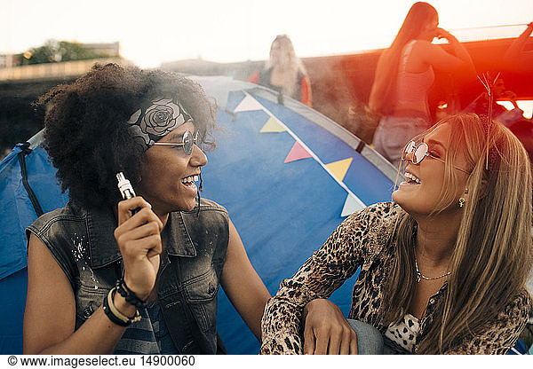 Smiling man with eletronic ciagrette looking at woman against tent