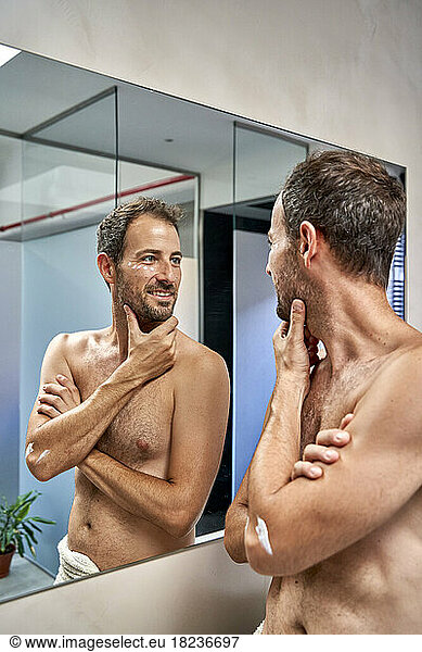 Smiling man with hand on chin looking in mirror