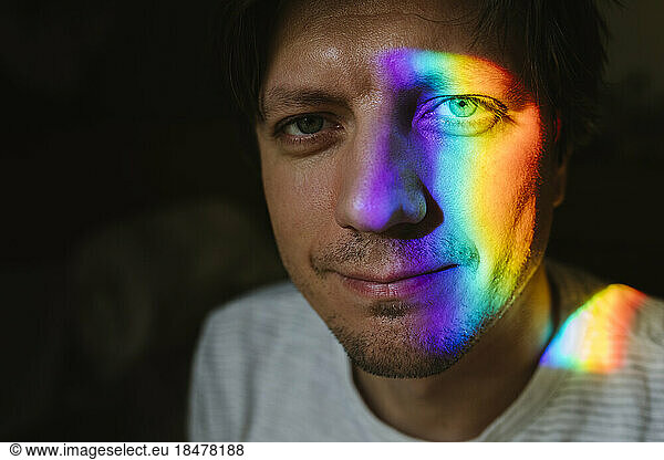 Smiling man with rainbow light on face