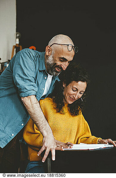 Smiling man with woman preparing financial bills at home