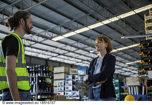 Smiling manager having discussion with colleague in factory