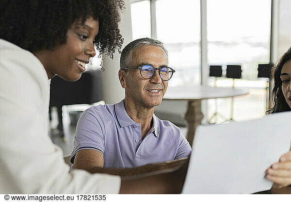 Smiling mature businessman discussing document with businesswomen