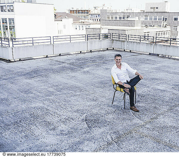 Smiling mature businessman sitting on building terrace