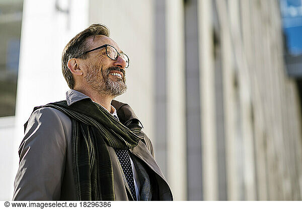Smiling mature businessman wearing eyeglasses outside office building