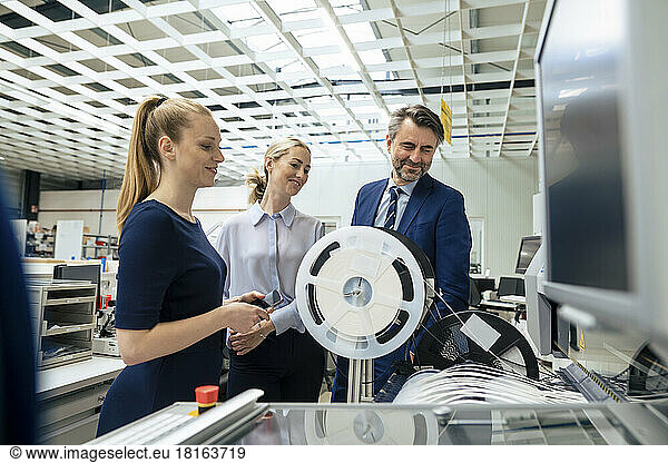 Smiling mature businessman with colleagues operating machinery at industry