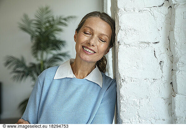 Smiling mature businesswoman leaning on wall