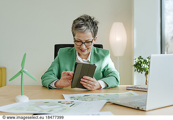 Smiling mature businesswoman working on tablet PC in office