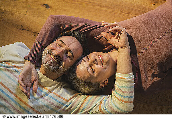 Smiling mature couple resting on floor at home