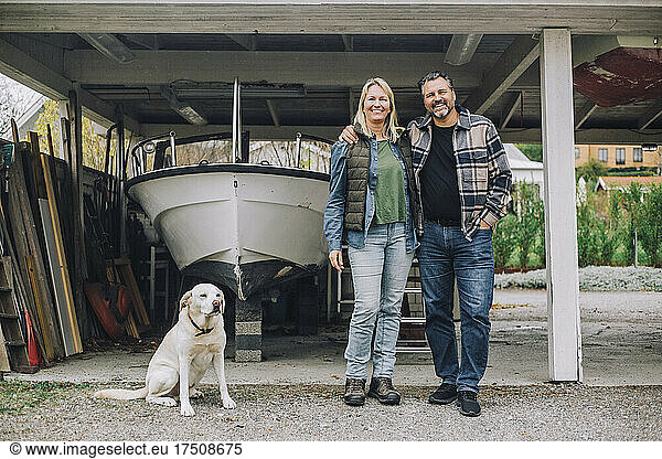 Smiling mature couple with dog in garage