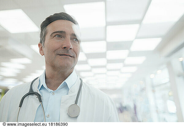 Smiling mature doctor with stethoscope seen through glass