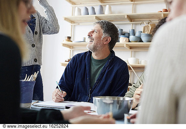 Smiling mature male student talking with female instructor in art studio