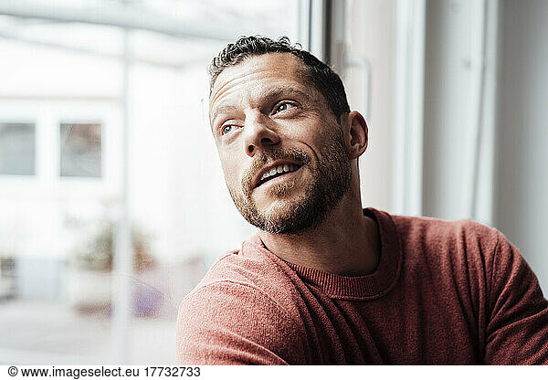 Smiling mature man looking out of window at home