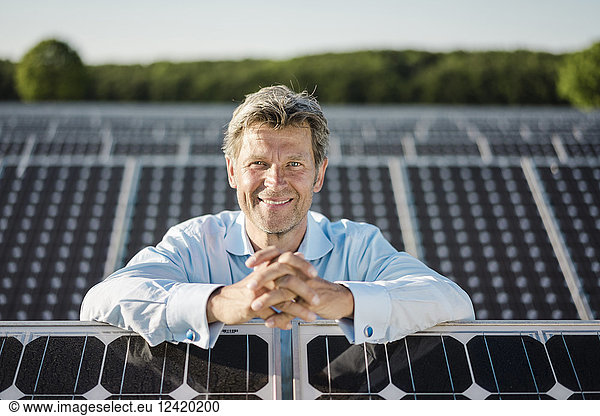 Smiling mature man standing in solar plant
