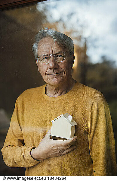 Smiling mature man standing with model home