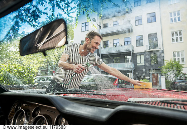 Smiling mature man washing his car