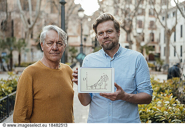 Smiling mature man with father showing diagram on tablet PC