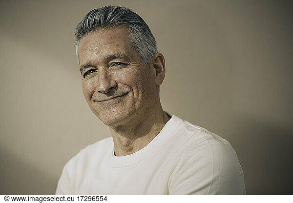 Smiling mature man with gray hair against beige wall