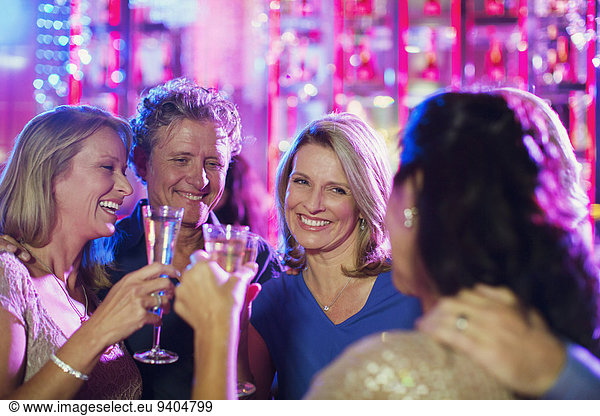 Smiling mature people toasting with champagne flutes in nightclub