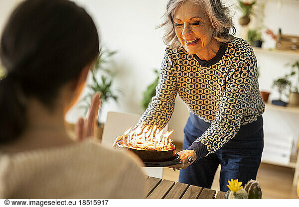 Smiling mature woman celebrating daughter's birthday at home