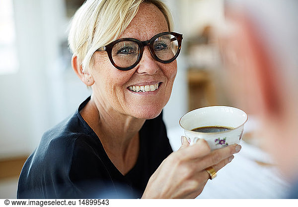 Smiling mature woman holding coffee cup while looking away at home