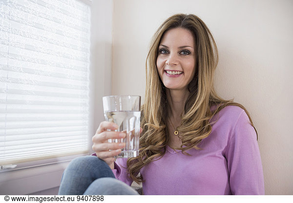 Smiling mature woman holding glass at the window