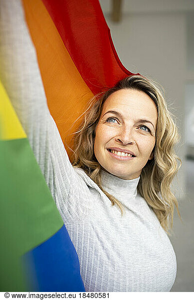 Smiling mature woman holding multi colored flag