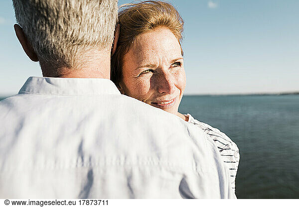 Smiling mature woman hugging man on sunny day