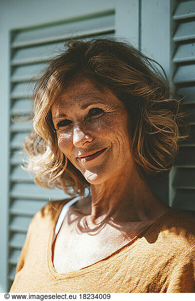 Smiling mature woman leaning on door