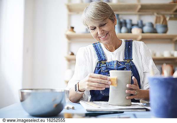 Smiling mature woman learning pottery in art class