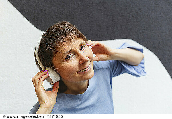 Smiling mature woman listening music with headphones