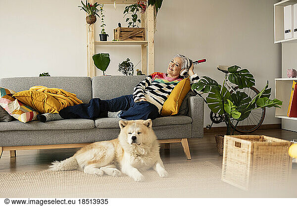 Smiling mature woman relaxing and listening to music at home