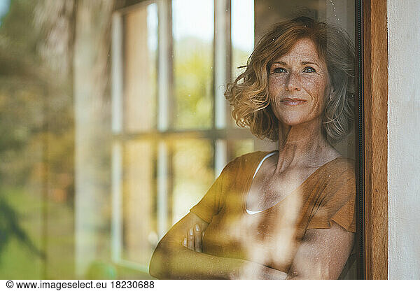 Smiling mature woman seen through glass window